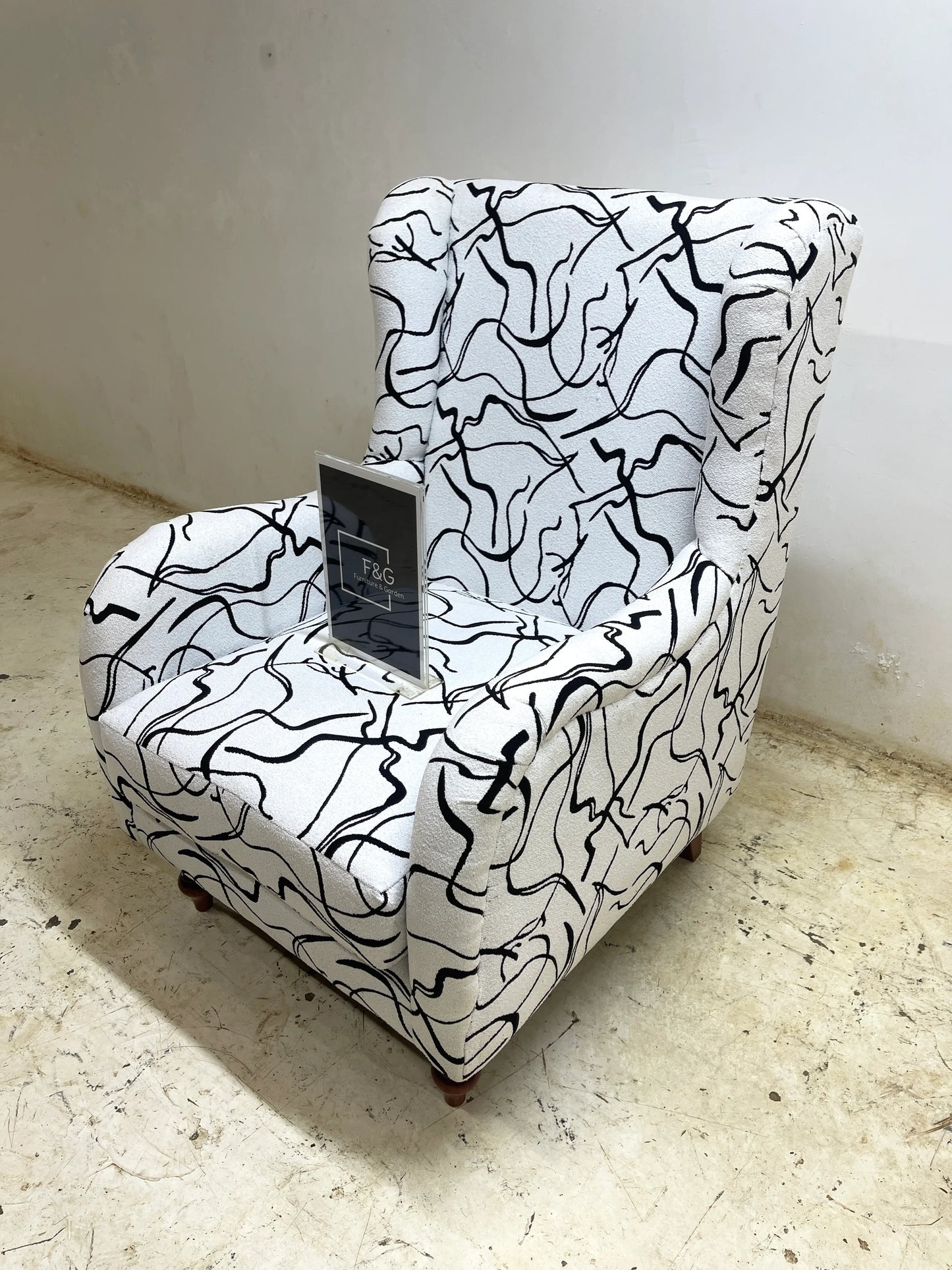Modern wingback armchair with abstract black line pattern on white upholstery, wooden legs