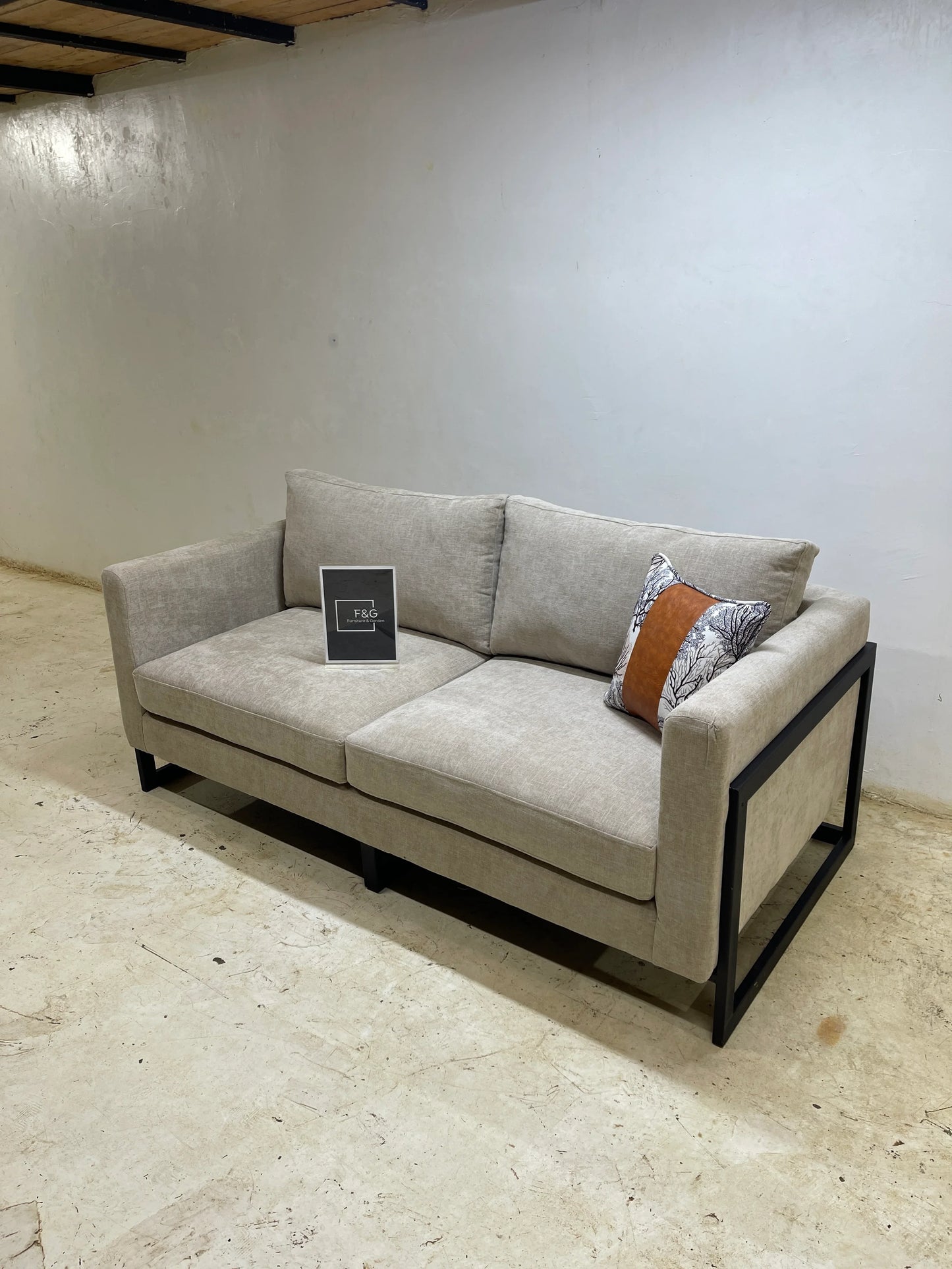 Modern beige fabric sofa with black metal frame and decorative pillow in minimalist room