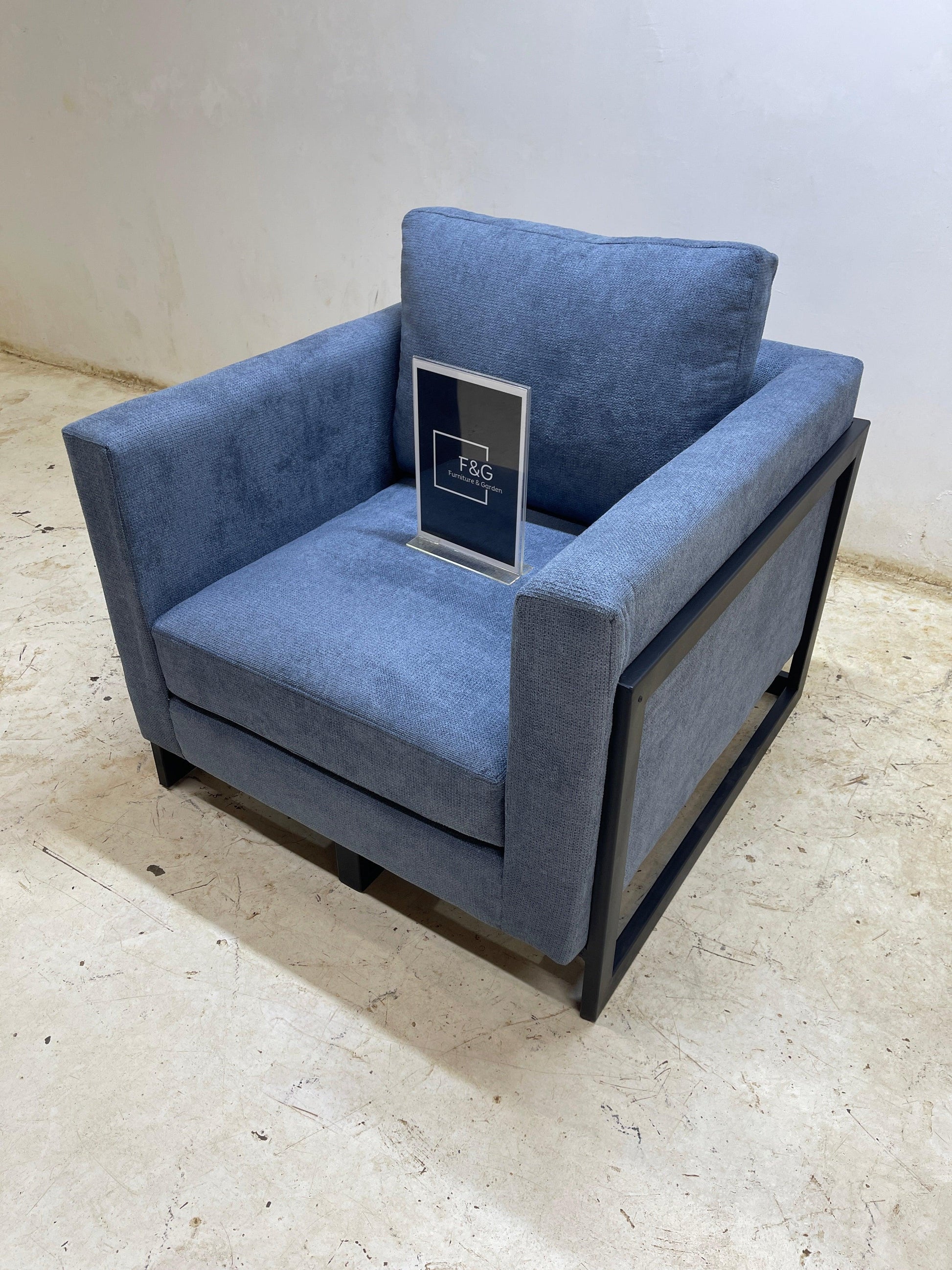 Blue fabric armchair with black metal frame on beige concrete floor