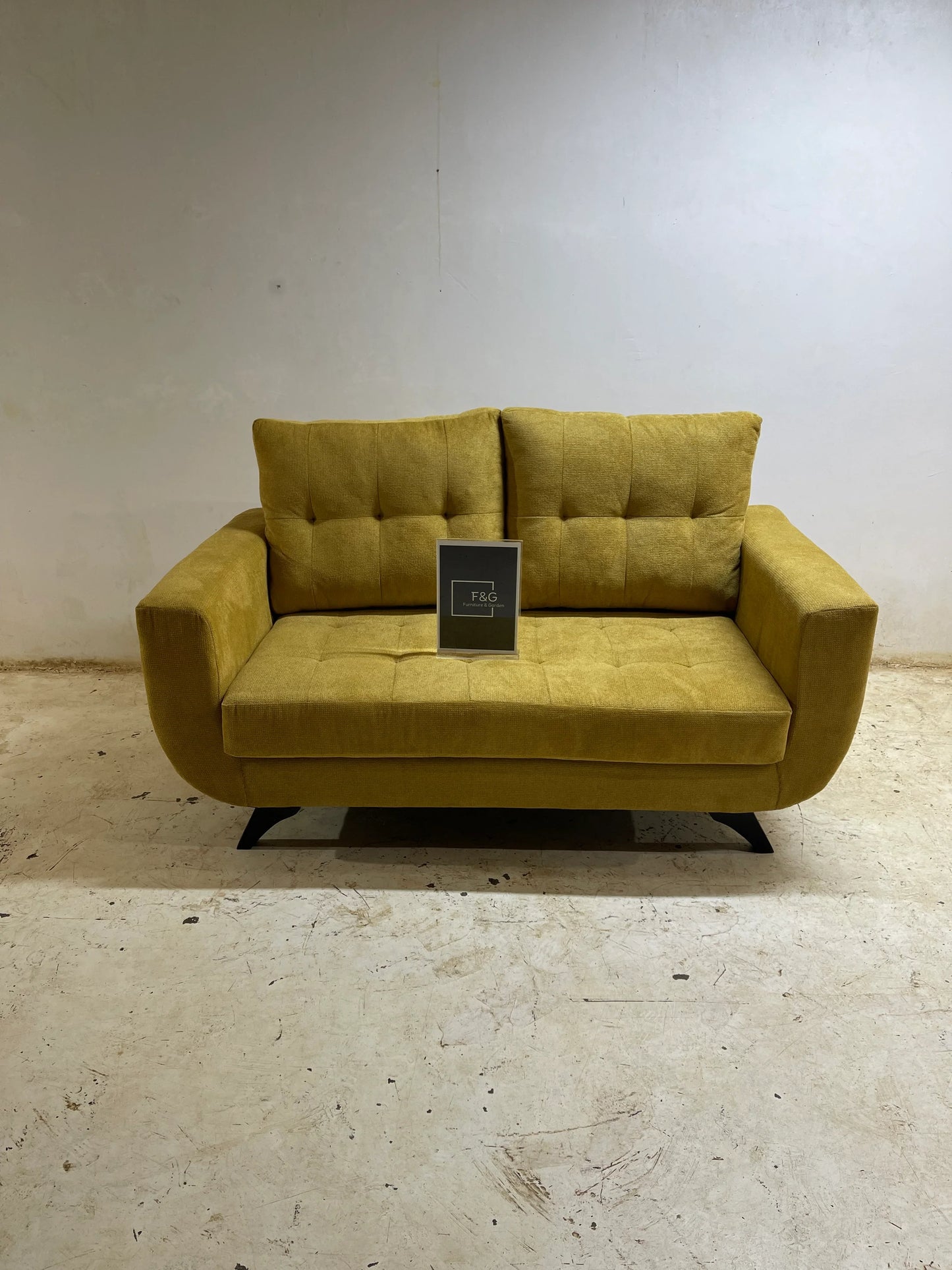 Modern mustard yellow two-seater sofa with tufted cushions on worn concrete floor