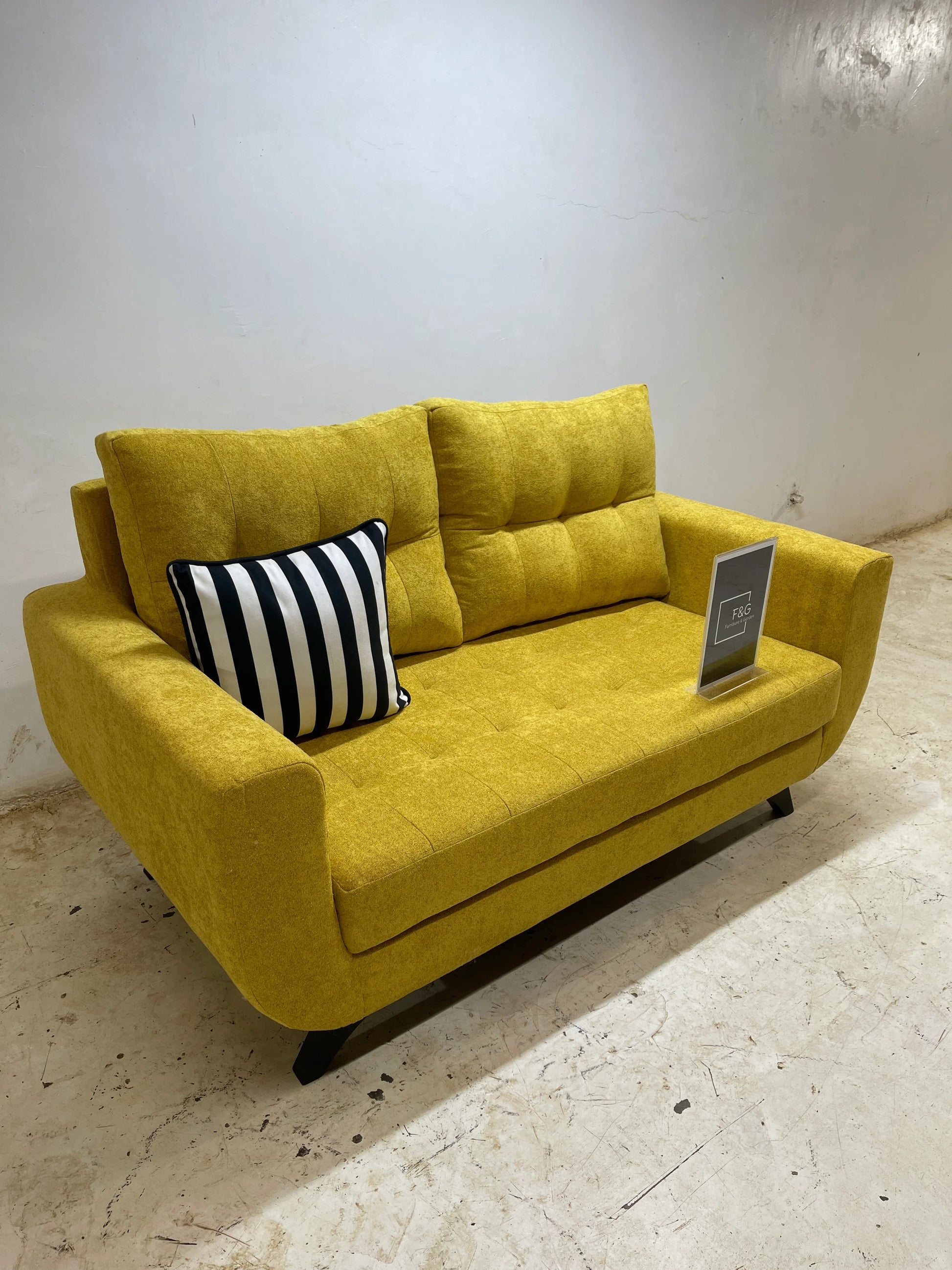 Yellow modern fabric sofa with black legs and black-and-white striped cushion in a minimalist room