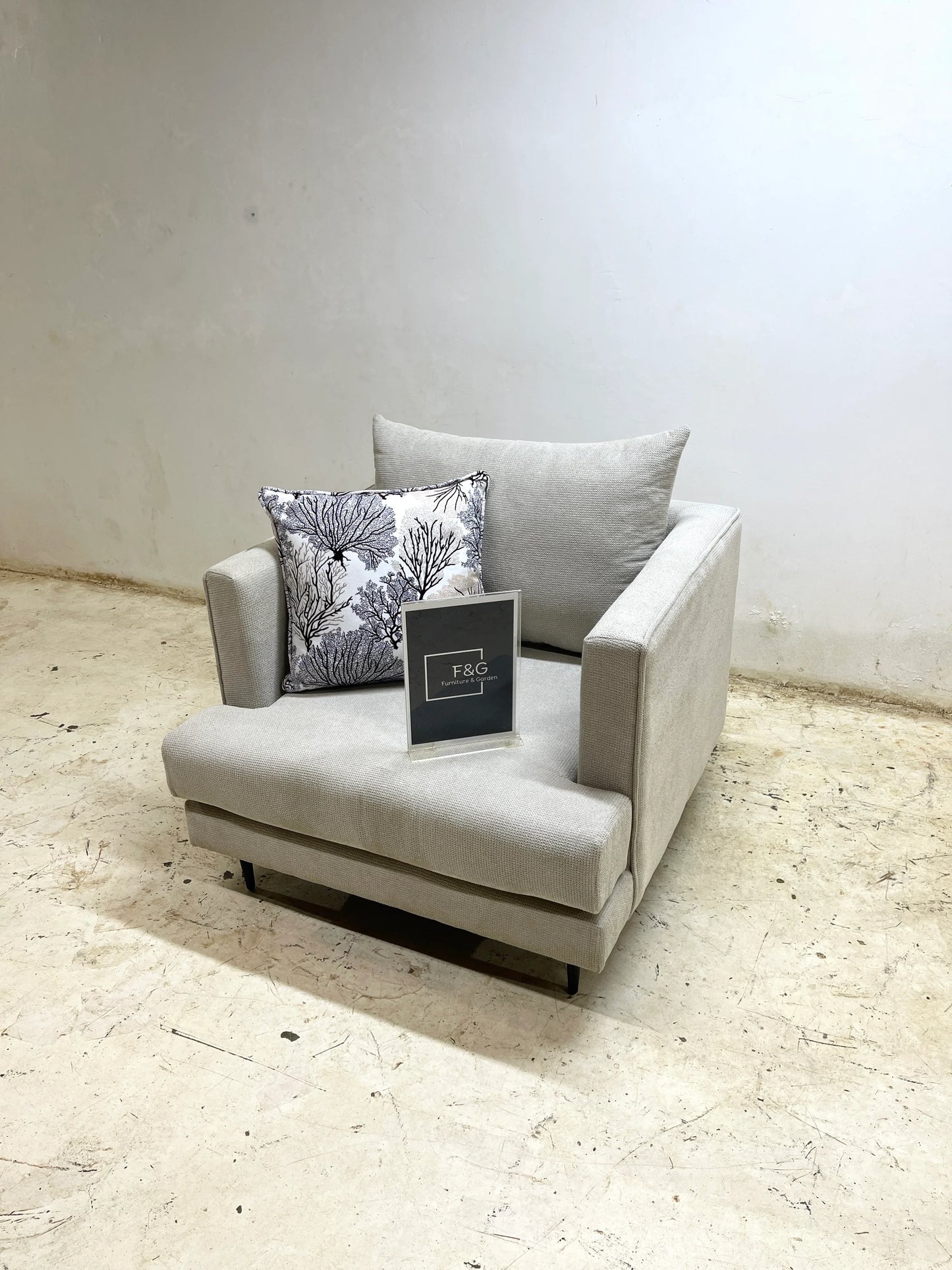 Modern light gray armchair with decorative black and white coral pattern pillow in minimalist room