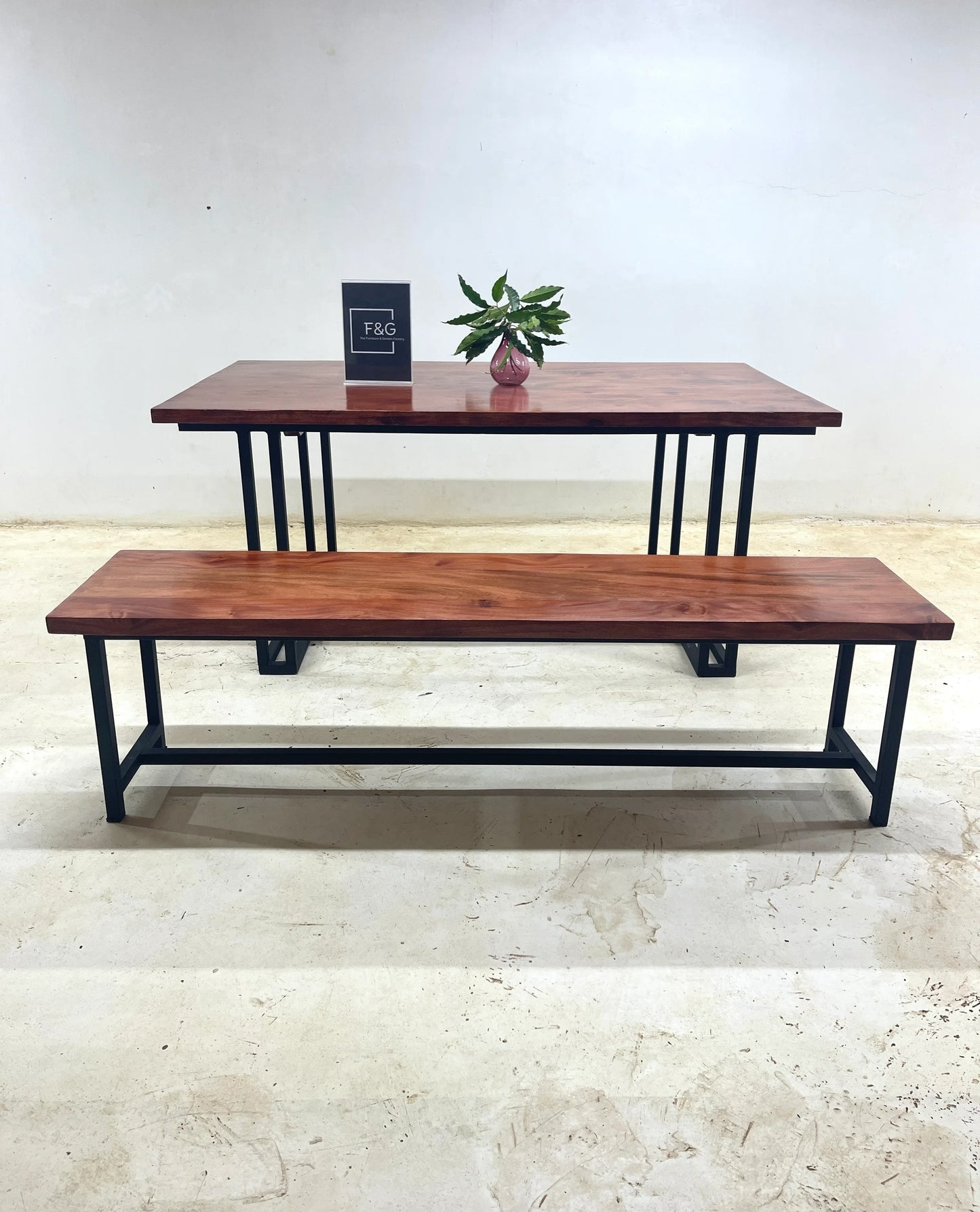 Modern wooden dining table with black metal legs and matching bench on concrete floor