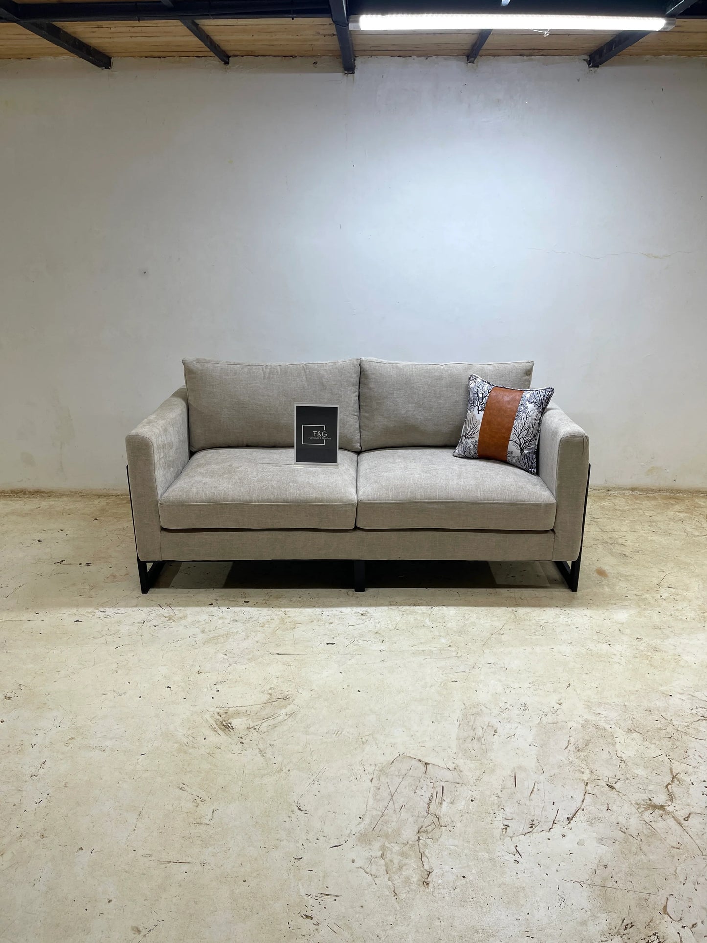 Modern beige fabric sofa with black metal legs, decorative pillow, and simple minimal room setting