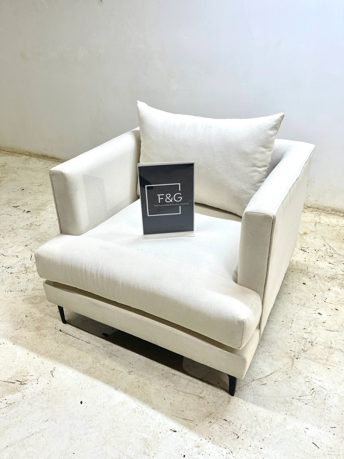 Modern white upholstered armchair with square cushion and F&G Furniture & Garden Factory sign